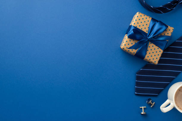 father's day concept. top view photo of polka dot gift box with satin ribbon bow cup of coffee cufflinks and blue necktie on isolated blue background with empty space - fathers day imagens e fotografias de stock