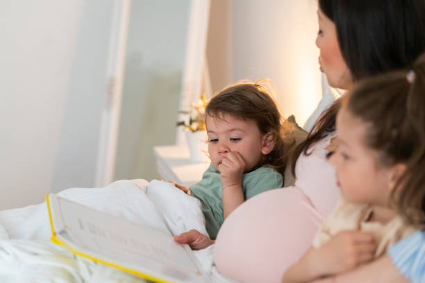 istock Pregnant mother reading book to daughters 1399738051