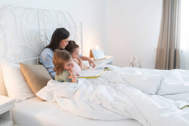 istock Pregnant mother reading book to daughters 1399738100