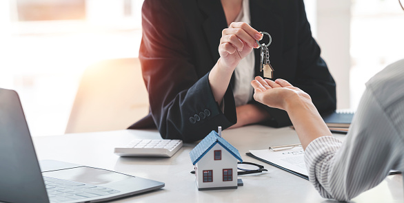 Compra de bienes raíces y concepto de acuerdo. Los agentes inmobiliarios acuerdan comprar una casa y dar las llaves a los clientes en las oficinas de su agencia. photo