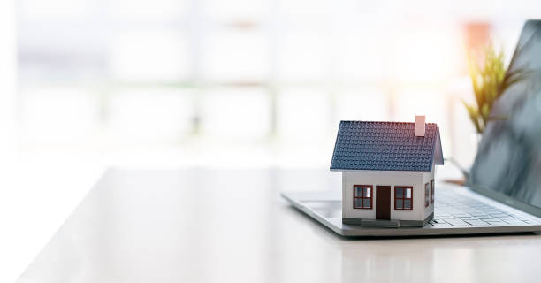 istock House model on laptop computer on wooden table with copy space, real estate concept. 1399739769