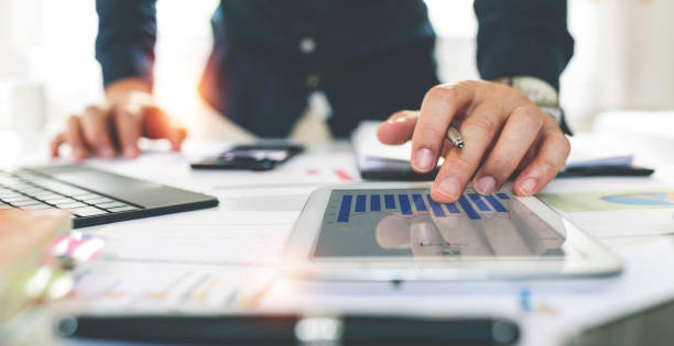 un homme d’affaires ou un expert financier analyse le graphique du rapport d’affaires et le tableau des finances sur tablette au bureau. concept d’économie financière, d’activité bancaire et de recherche boursière. - tax graph financial report finance photos et images de collection