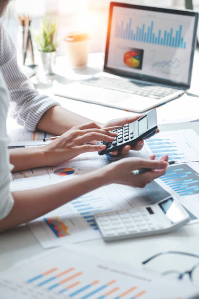 Businesswoman working at office with documents on her desk, calculating and analyzing the financial report.