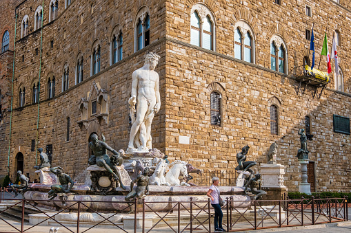 Tourist posing in front of the Fountain of Neptune of Florence, located in Piazza della Signora, created by Bartolomeo Ammannati between 1560 and 1574