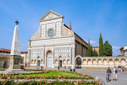 Tourists strolling in the large square where overlooks the Basilica of Santa Maria Novella, one of the most notable churches of Florence