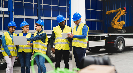 Multiethnic engineers working inside robotic factory - Industrial and technology concept - Main focus on right man hand holding tablet