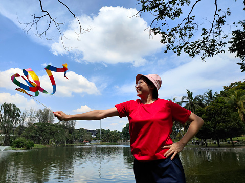 An Asian woman is learning and practicing gymnastic ribbon at public park.