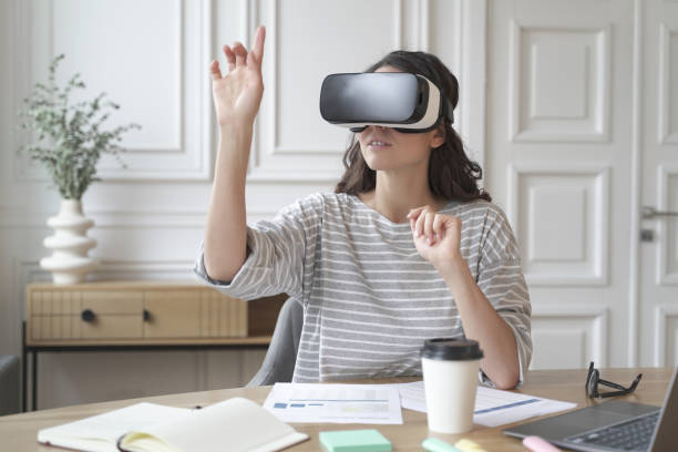 istock Young focused woman wearing virtual reality headset watching 360 degree content at work 1399750354