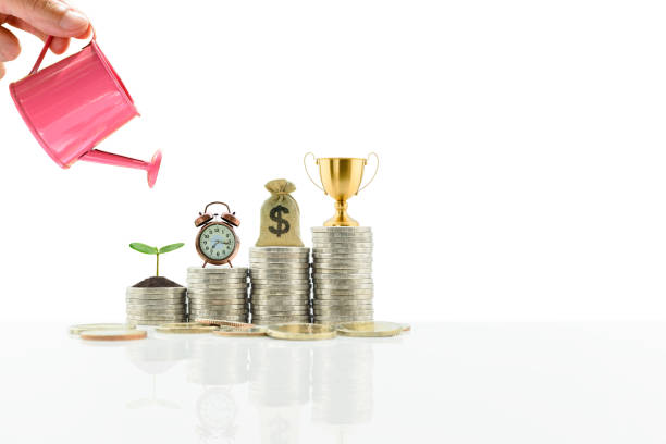 istock Successful saving plan, financial strategies concept : Trophy cup, dollar bag, clock, young green small tree on stacks of coins. 1399752719