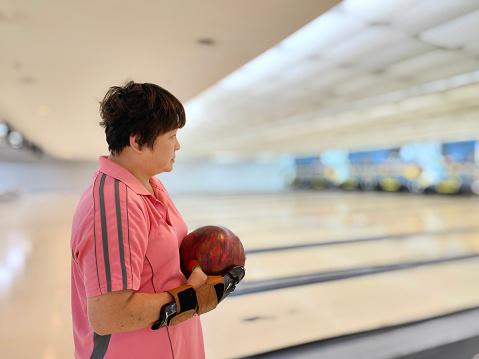 An Asian woman is practicing bowling preparing for upcoming tournament.