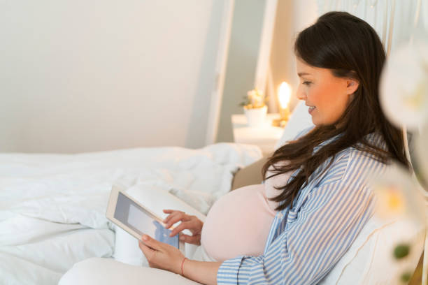 istock Pregnant woman in bed using digital tablet 1399754138