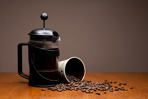 Black Filter coffee pot with a mug and coffee beans spilling out of it beautifully isolated on a plain background