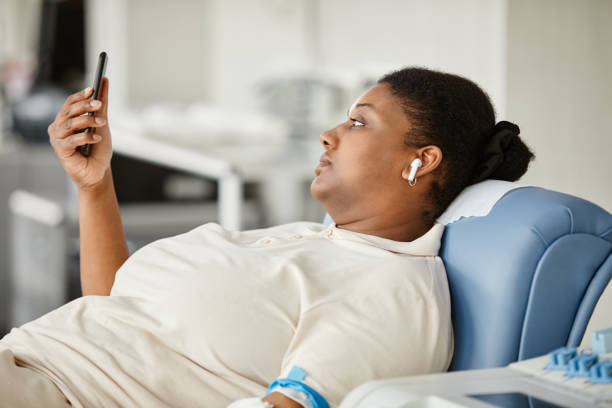 mulher no centro de doação de sangue usando smartphone - blood donation audio - fotografias e filmes do acervo