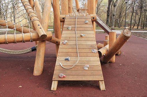 Climbing and ladder in outdoor modern children wooden playground in a public park of city. Eco-friendly lifestyle rest and childhood concept of safety environmentally infrastructure the park