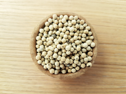 White pepper seeds in a wooden bowl on the table