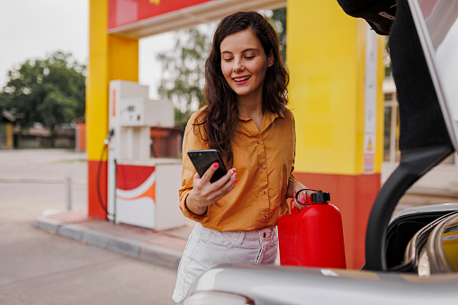Young smiling woman with gas can on gas station