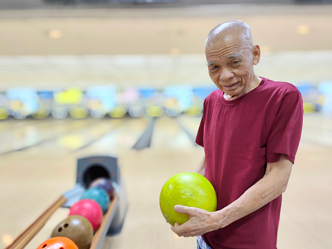 An Asian senior man is learning for bowling.