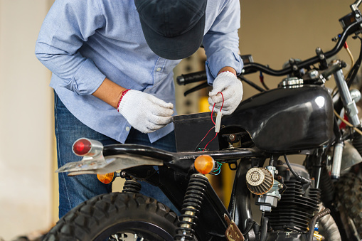 Man repairing motorcycle in repair shop, Mechanic fixing motorbike in workshop garage, Repairing and maintenance concepts