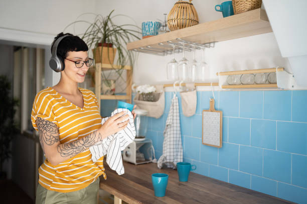 Modern young Caucasian woman doing chores in the kitchen while listen to music on headphones stock photo