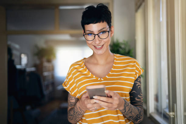 porrait of young caucasian woman, with short hair using mobile phone - 時尚人 個照片及圖片檔