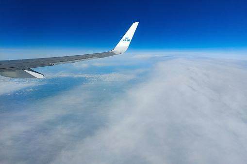 Amsterdam, Netherlands - May 18 2022: the wing of a KLM Royal Dutch Airlines plane above the clouds. KLM is a the flag carrier airline of the Netherlands.