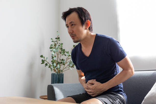 istock Man Sitting On Sofa Having a Stomach ache At Home. 1399761190