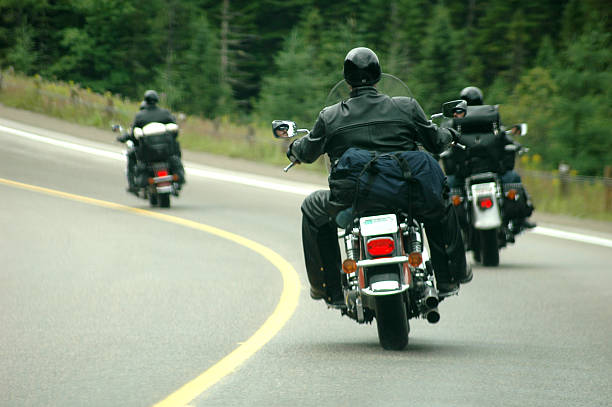 three individuals riding motorbikes along a scenic road