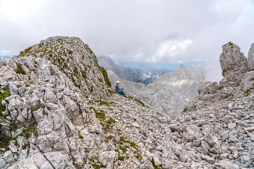 Side view of one woman relaxing on top of mountain peak in highlands of Triglav national park, Julian Alps