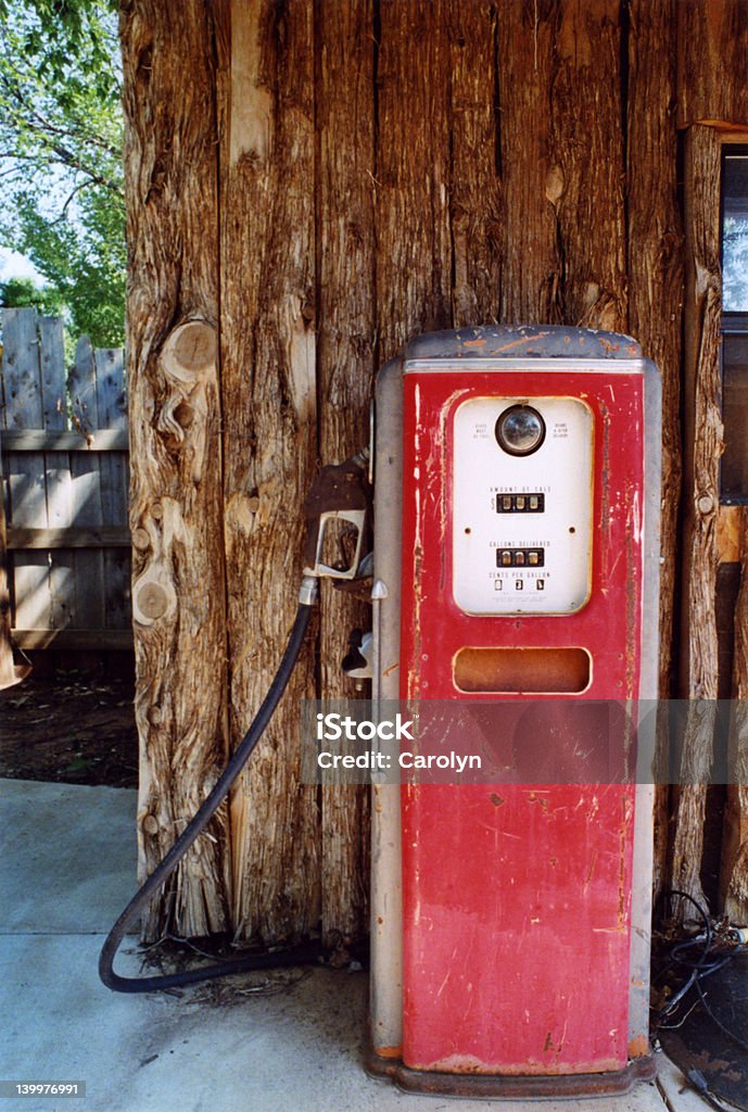 Antique Gas Pump With Log Wall Red painted weathered vintage gasoline pump displayed against rustic log wall. Antique Stock Photo