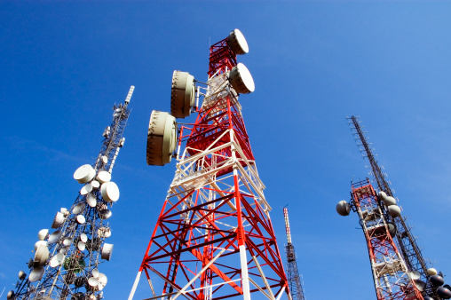 Telecommunications towers on blue sky, a red and white, the other white, antennas for television, radio, and mobile phones.