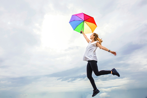 Colorful umbrella carrying a woman into the sky