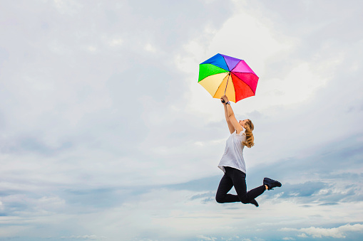 Colorful umbrella carrying a woman into the sky