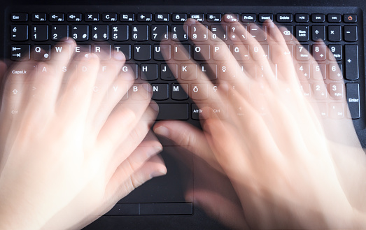 Man is using keyboard quickly for writing on laptop. Top view of caucasian man blurred hand on black computer keyboard.