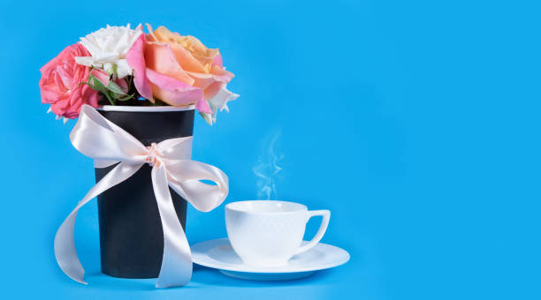 Bouquet of rose flowers and coffee cup with smoke on blue background.  Copy space stock photo