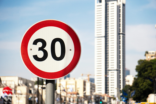 Speed limit traffic signs in israeli town Ramat-Gan with a high building on the background
