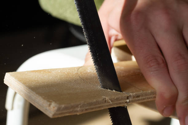 Sawing wooden plywood with a jigsaw, sawdust flying from the saw to the sides stock photo