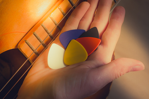 Multi-colored guitar picks on the guitarist's hand.