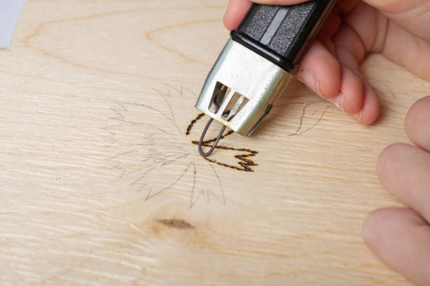 istock Burn out a drawing on a wooden board with an electric device with a scorcher 1399773703
