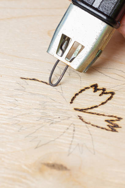 istock Burn out a drawing on a wooden board with an electric device with a scorcher 1399773710