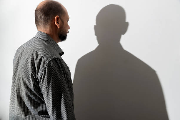 istock Portrait of a man and his shadow against white wall background. 1399774721