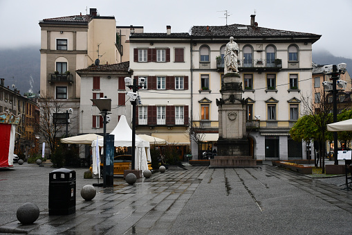 Como, Italy - December 19, 2019: Statue of physicist Alessandro Volta by Pompeo Marchesi (1838) in Piazza Volta, on a rainy day.