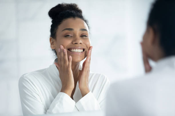 femme d’ethnie africaine souriante et séduisante faisant de la routine de soins de la peau. - mid adult women human skin neat good condition photos et images de collection