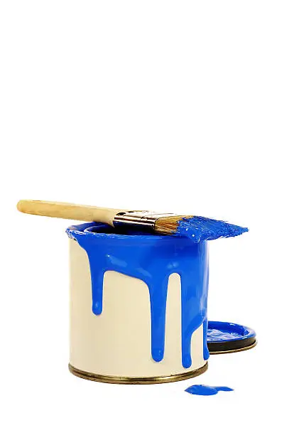 can of blue paint with paint spilling over edge and with a paint brush on top of can isolated on white