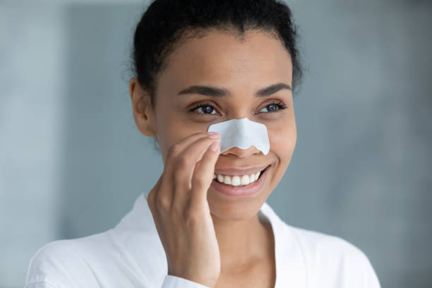 istock Happy young african woman using nose cleansing strip. 1399779883