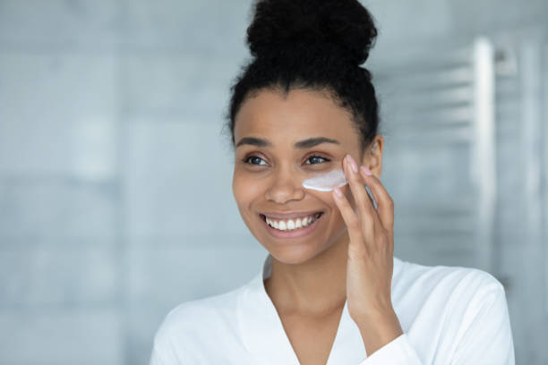 istock Smiling attractive millennial african woman applying creme. 1399779891