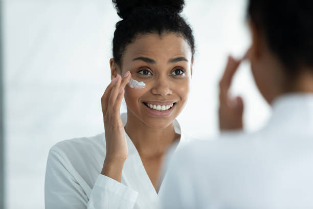 istock Happy beautiful young african woman applying creme. 1399779893