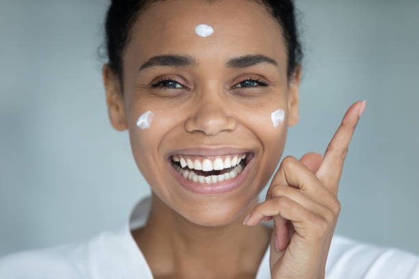 istock Young attractive african american woman applying creme on cheeks. 1399779904