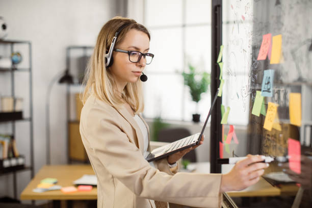 istock Woman in headset writing on glass wall during video call 1399780557