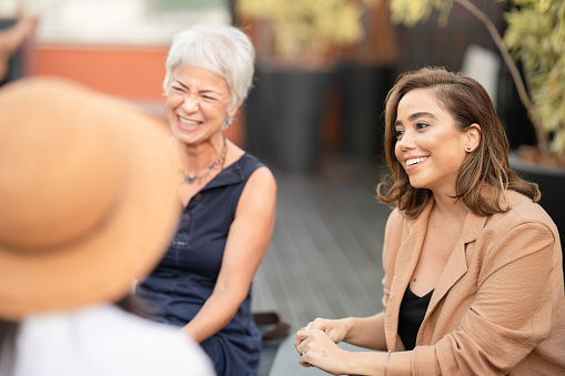 Diverse group of women smiling and talking together outside on a terrace in the summertime