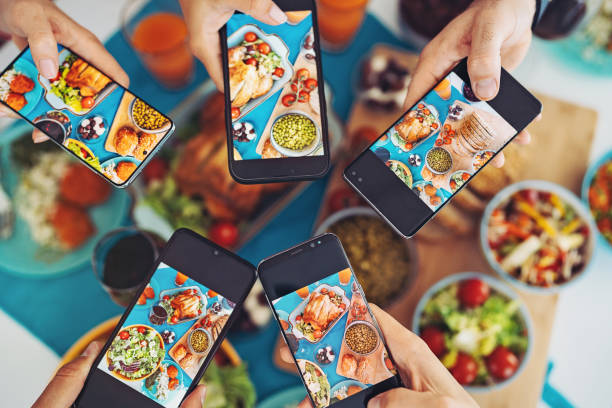 Group of friends taking pictures of the food with their phones stock photo